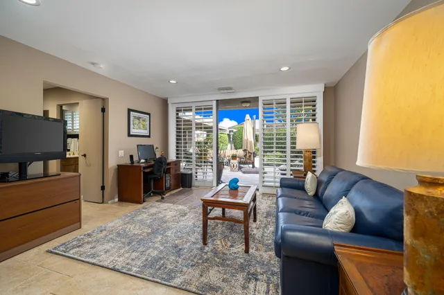 a living room with furniture a flat screen tv and a refrigerator