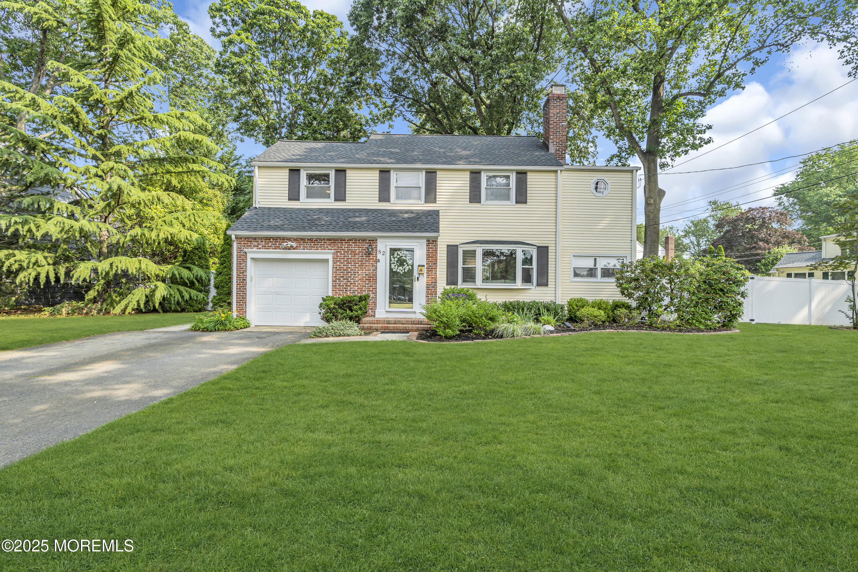 a front view of a house with a yard and trees