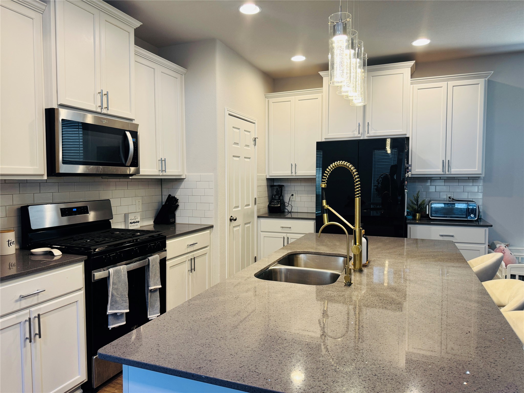 349 Rend Drive Leander, TX 78641 - Photo 8 of 21 Kitchen with black appliances, white cabinets, and a kitchen bar