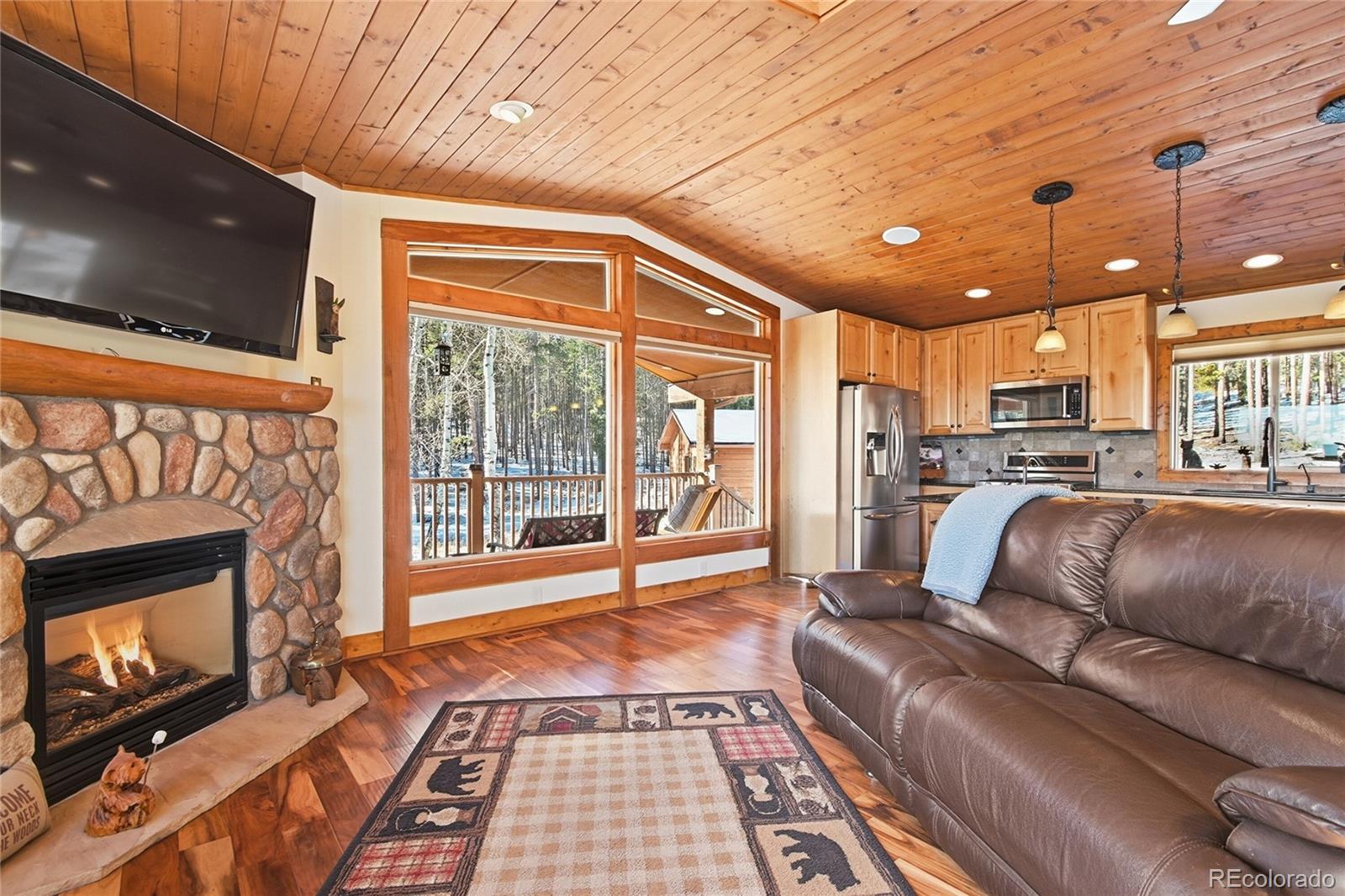 8790 South Warhawk Road Conifer, CO 80433 - Photo 12 of 41 a living room with a couch a fireplace and a flat screen tv