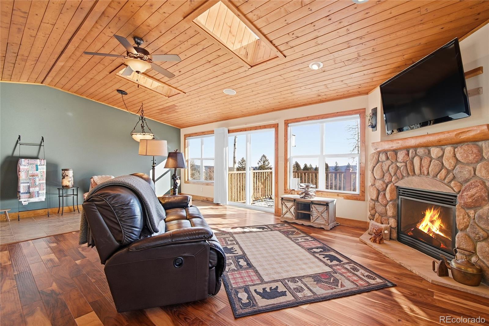 8790 South Warhawk Road Conifer, CO 80433 - Photo 13 of 41 a living room with furniture a flat screen tv and a fireplace