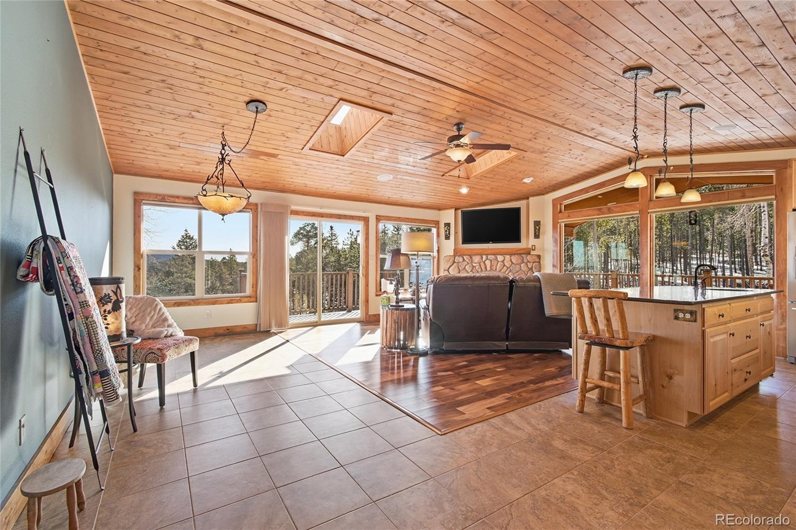 8790 South Warhawk Road Conifer, CO 80433 - Photo 4 of 41 a living room with furniture a flat screen tv and floor to ceiling window
