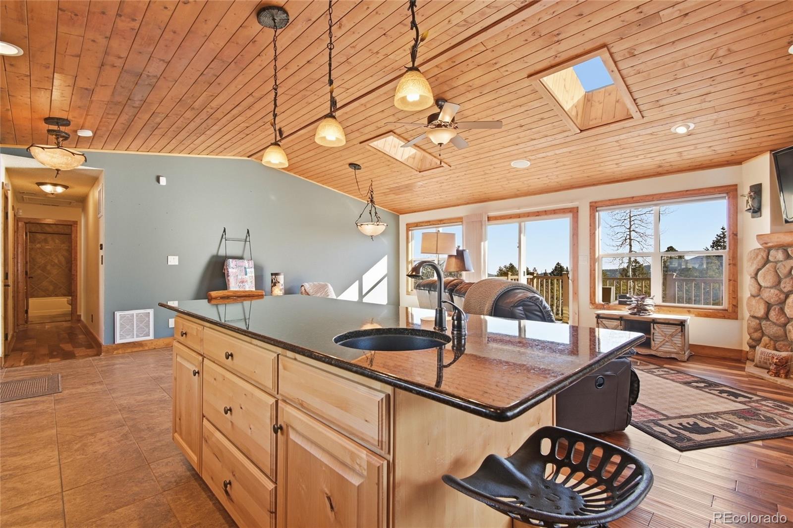 8790 South Warhawk Road Conifer, CO 80433 - Photo 8 of 41 a kitchen with granite countertop a stove and white cabinets with wooden floor