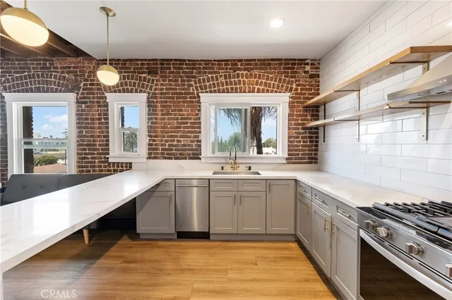 a kitchen with stainless steel appliances granite countertop a sink and wooden floors