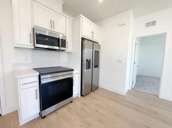 a kitchen with stainless steel appliances white cabinets a stove and a microwave