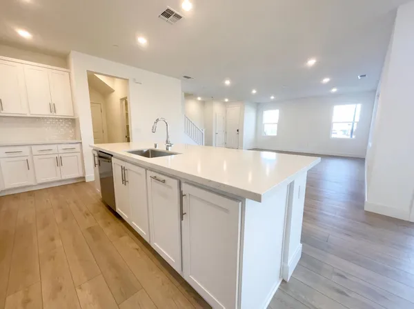 a large white kitchen with wooden floor