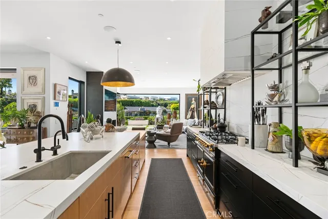 a view of a kitchen with kitchen island a large window cabinets a sink and stainless steel appliances