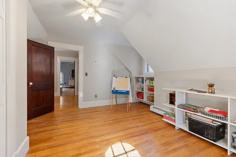 a view of a white house next to a yard with plants and large trees