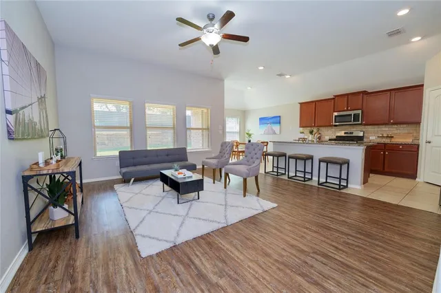 a living room with stainless steel appliances kitchen island granite countertop furniture a rug kitchen view and a fireplace