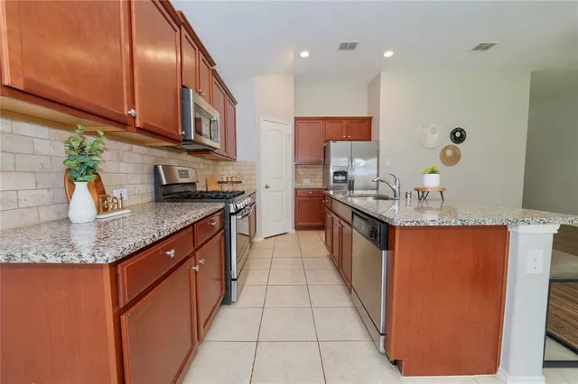 a kitchen with stainless steel appliances granite countertop a sink counter space cabinets a stove and a window
