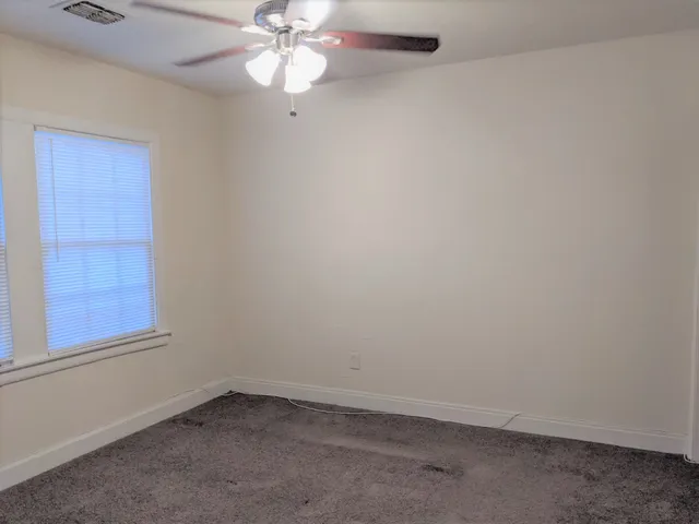 an empty room with a window and a fan