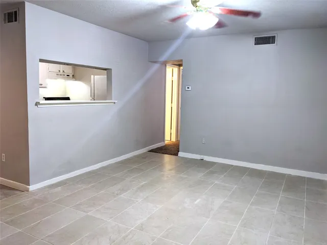 an empty room with a chandelier fan and windows