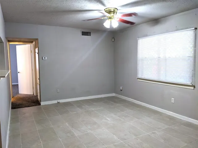 an empty room with windows and fan