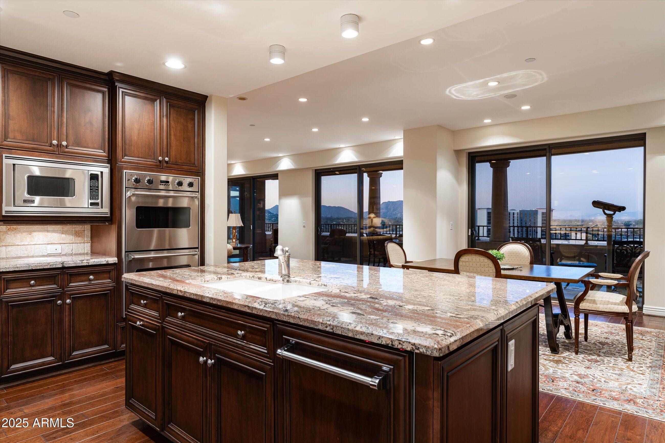 7181 East Camelback Road, Unit 1202 Scottsdale, AZ 85251 - Photo 12 of 47 a kitchen with granite countertop kitchen island stainless steel appliances a sink and a center island