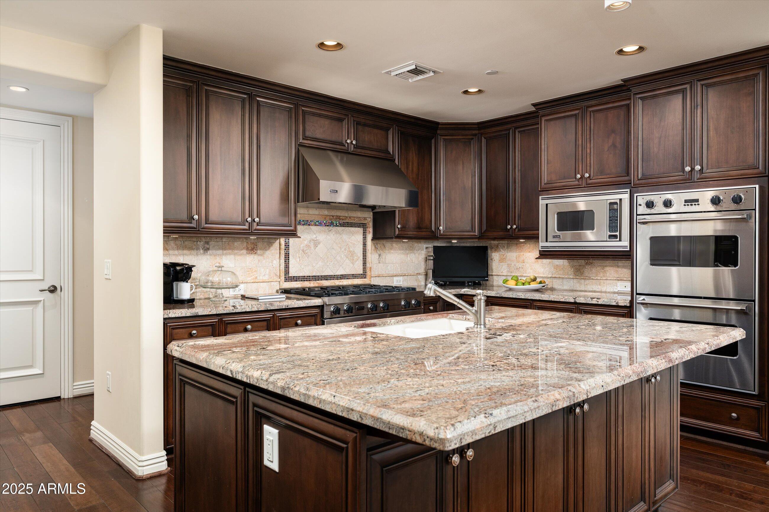 7181 East Camelback Road, Unit 1202 Scottsdale, AZ 85251 - Photo 13 of 47 a kitchen with wooden cabinets a microwave oven and a sink