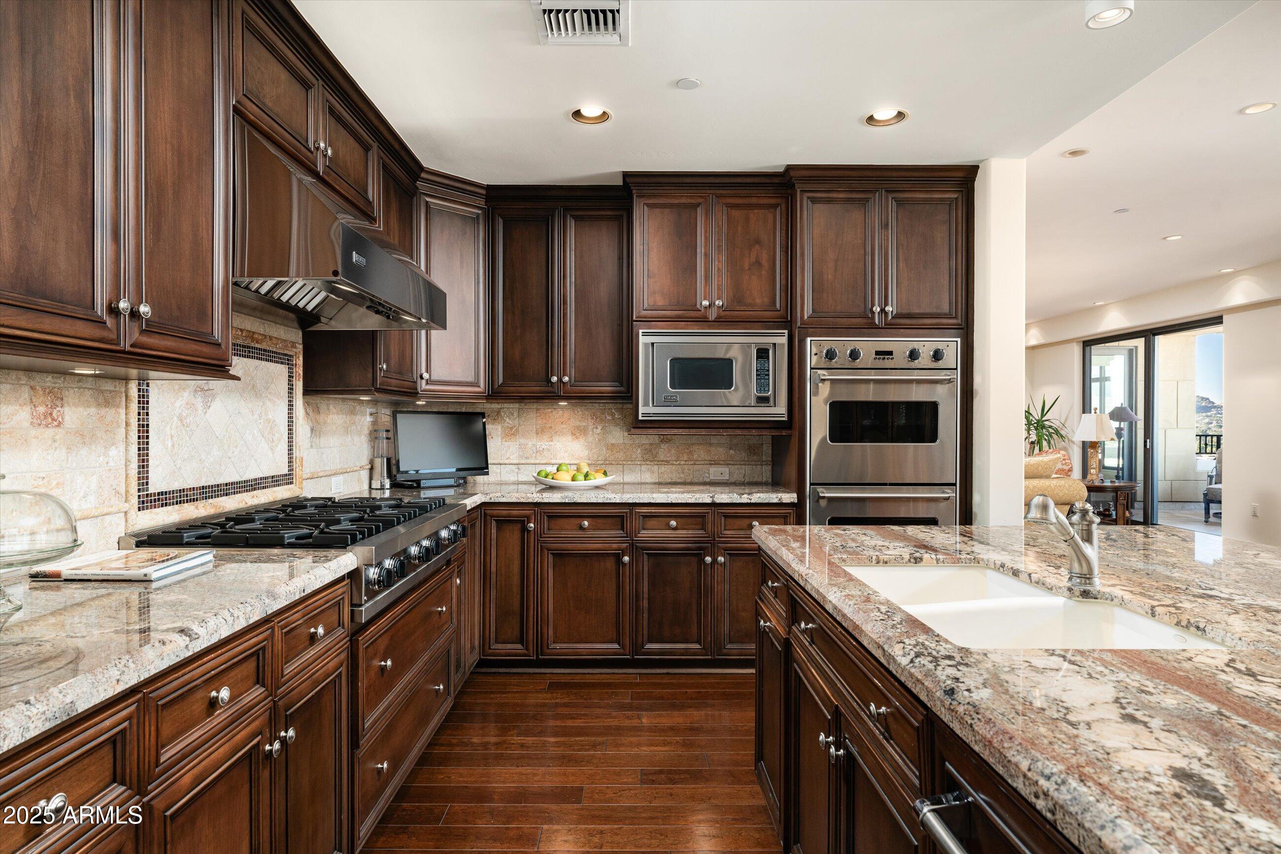7181 East Camelback Road, Unit 1202 Scottsdale, AZ 85251 - Photo 15 of 47 a kitchen with stainless steel appliances granite countertop a stove a sink dishwasher and a microwave oven with wooden cabinets