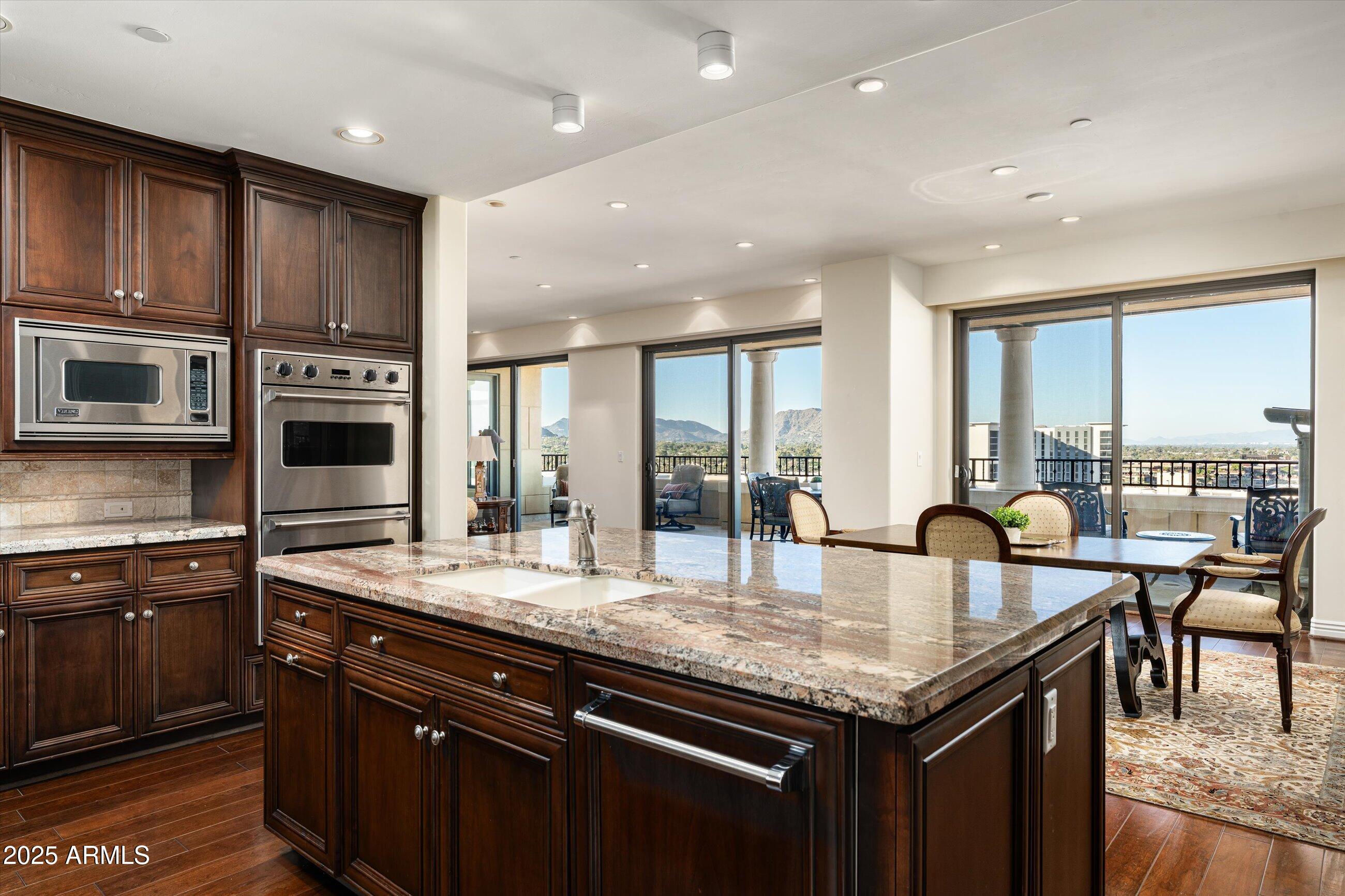 7181 East Camelback Road, Unit 1202 Scottsdale, AZ 85251 - Photo 16 of 47 a kitchen with granite countertop kitchen island stainless steel appliances a sink and a center island