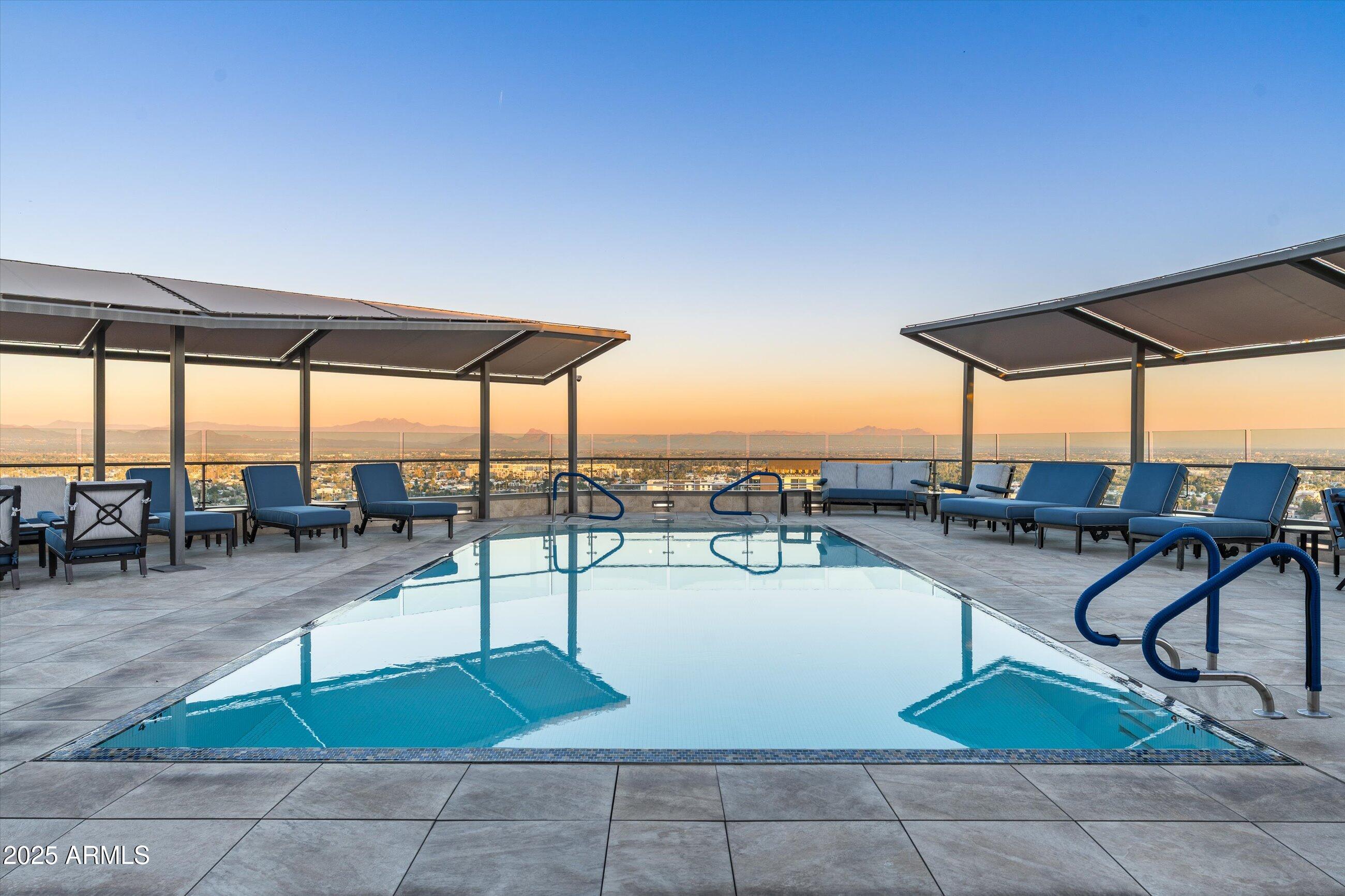 7181 East Camelback Road, Unit 1202 Scottsdale, AZ 85251 - Photo 45 of 47 a view of a swimming pool with a table and chairs under an umbrella