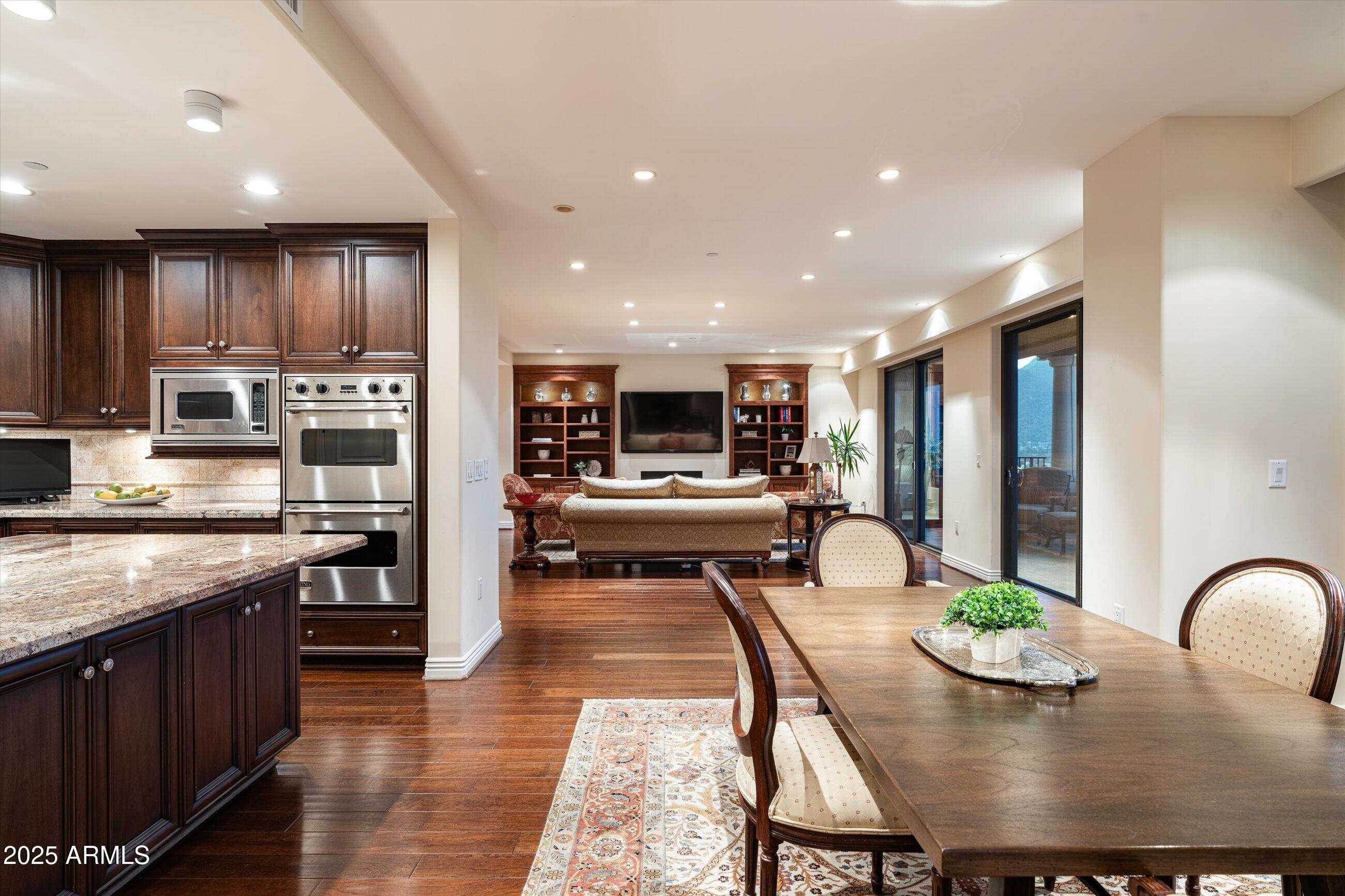 7181 East Camelback Road, Unit 1202 Scottsdale, AZ 85251 - Photo 9 of 47 a kitchen with stainless steel appliances granite countertop a stove top oven a dining table and chairs
