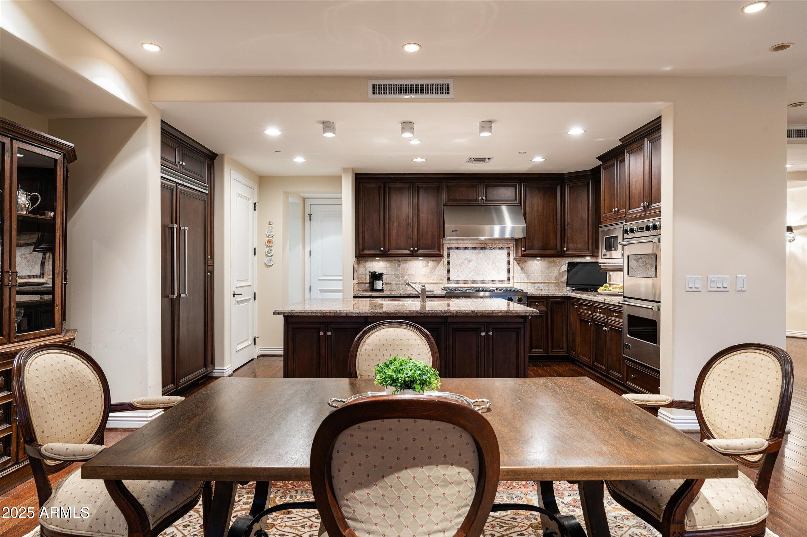 7181 East Camelback Road, Unit 1202 Scottsdale, AZ 85251 - Photo 10 of 47 a kitchen with stainless steel appliances granite countertop a stove a refrigerator a sink a dining table and chairs