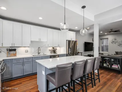 a kitchen with stainless steel appliances a dining table chairs sink and cabinets