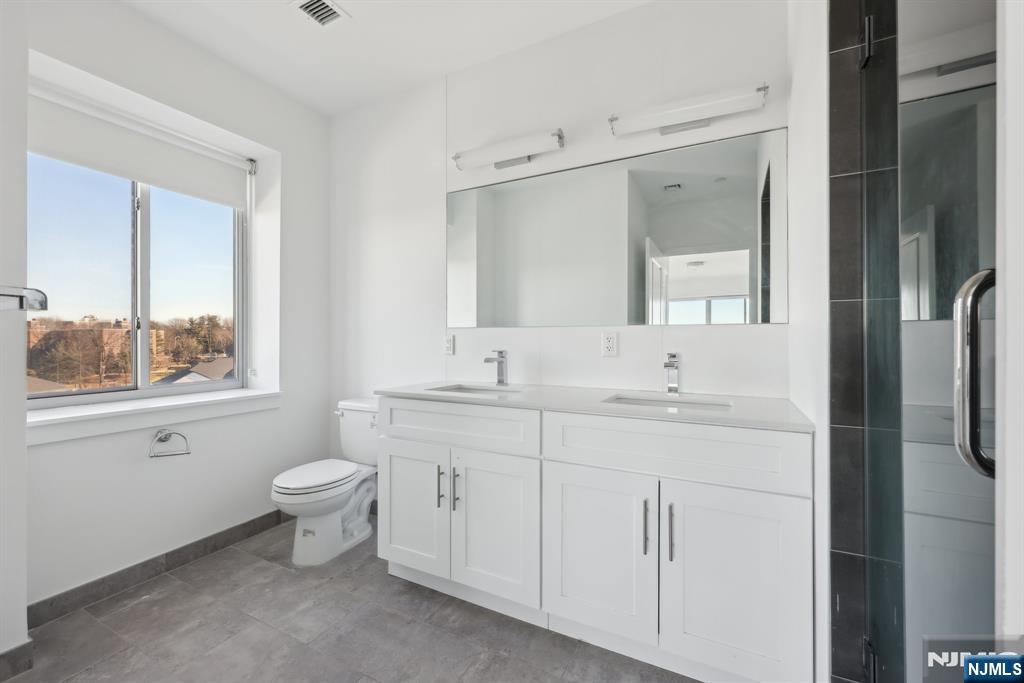 2 Executive Drive, Unit 809 Fort Lee, NJ 07024 - Photo 10 of 11 a bathroom with a double vanity sink a toilet and a mirror