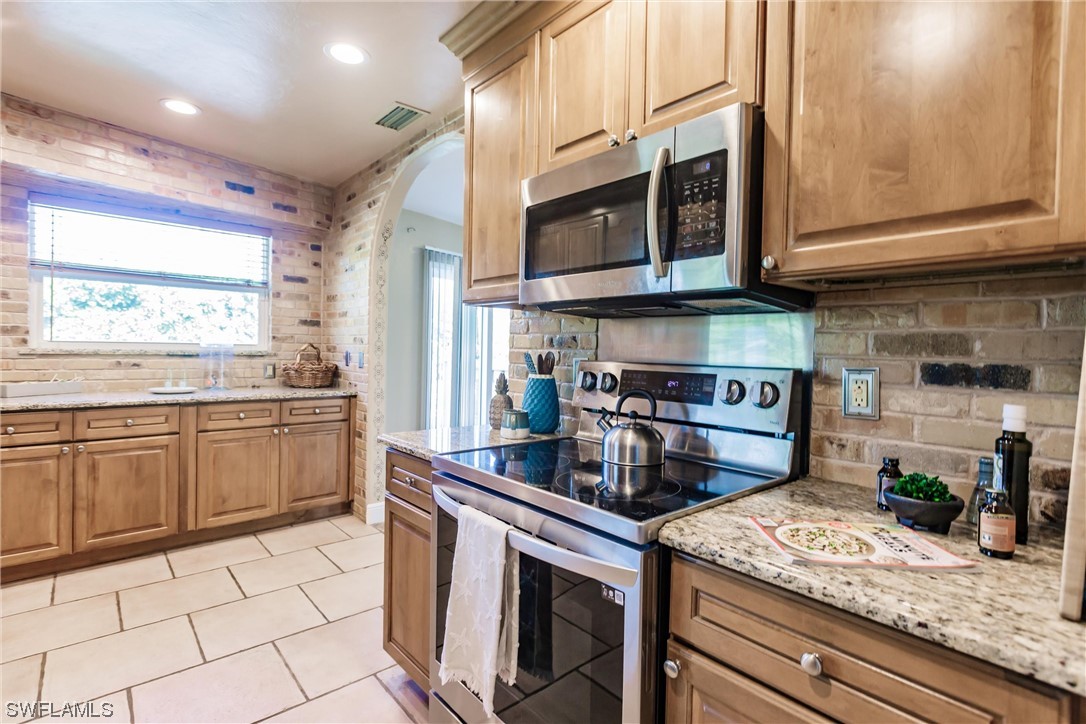 72 Pebble Beach Boulevard Naples, FL 34113 - Photo 8 of 15 a kitchen with stainless steel appliances granite countertop a stove a sink and a microwave