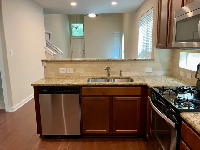 a kitchen with granite countertop a sink cabinets and stainless steel appliances