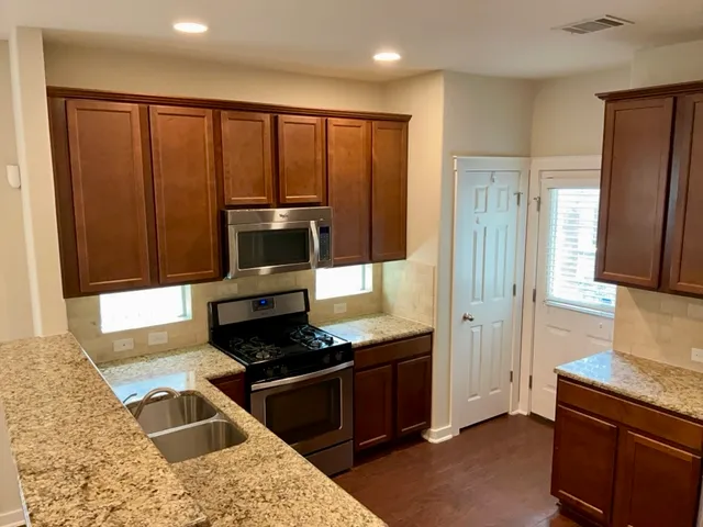 a kitchen with granite countertop wooden cabinets and stainless steel appliances