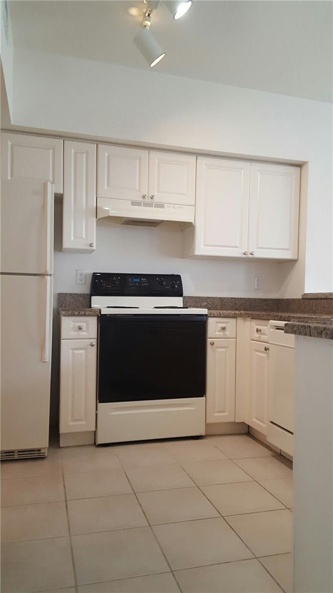 6720 West Sample Road, Unit 6720 Coral Springs, FL 33067 - Photo 3 of 8 a kitchen with granite countertop white cabinets and white appliances