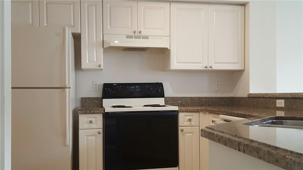 6720 West Sample Road, Unit 6720 Coral Springs, FL 33067 - Photo 5 of 8 a kitchen with stainless steel appliances granite countertop white refrigerator stove and white cabinets