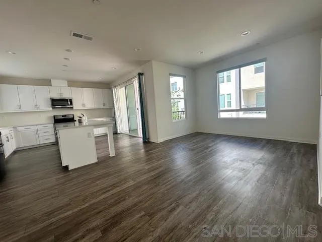 2036 Mayon Road Chula Vista, CA 91915 - Photo 13 of 49 a kitchen with granite countertop a stove a sink and white cabinets with wooden floor