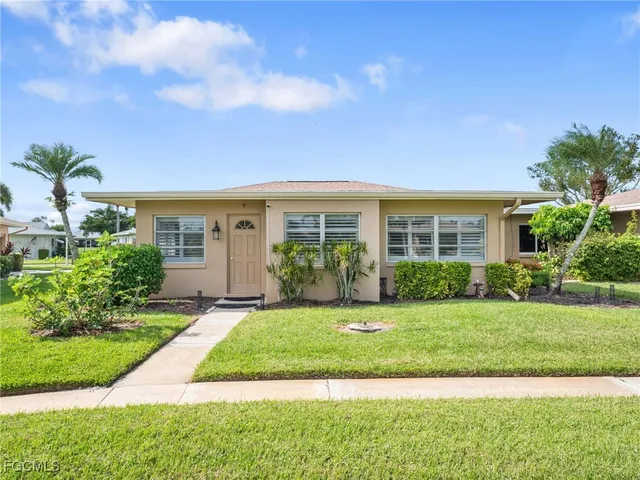a front view of a house with a yard and potted plants