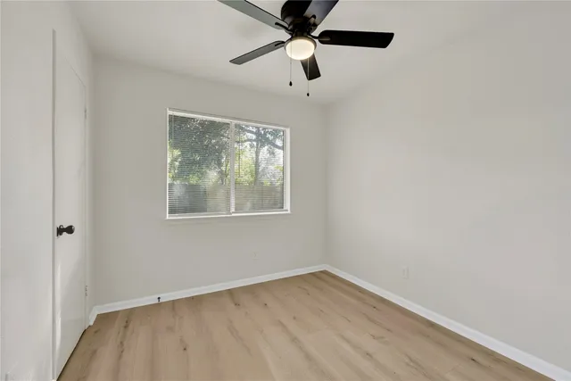 an empty room with a window and a fan
