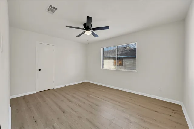 a view of empty room with wooden floor and fan