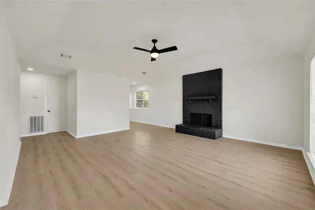 a view of an empty room with a ceiling fan and window