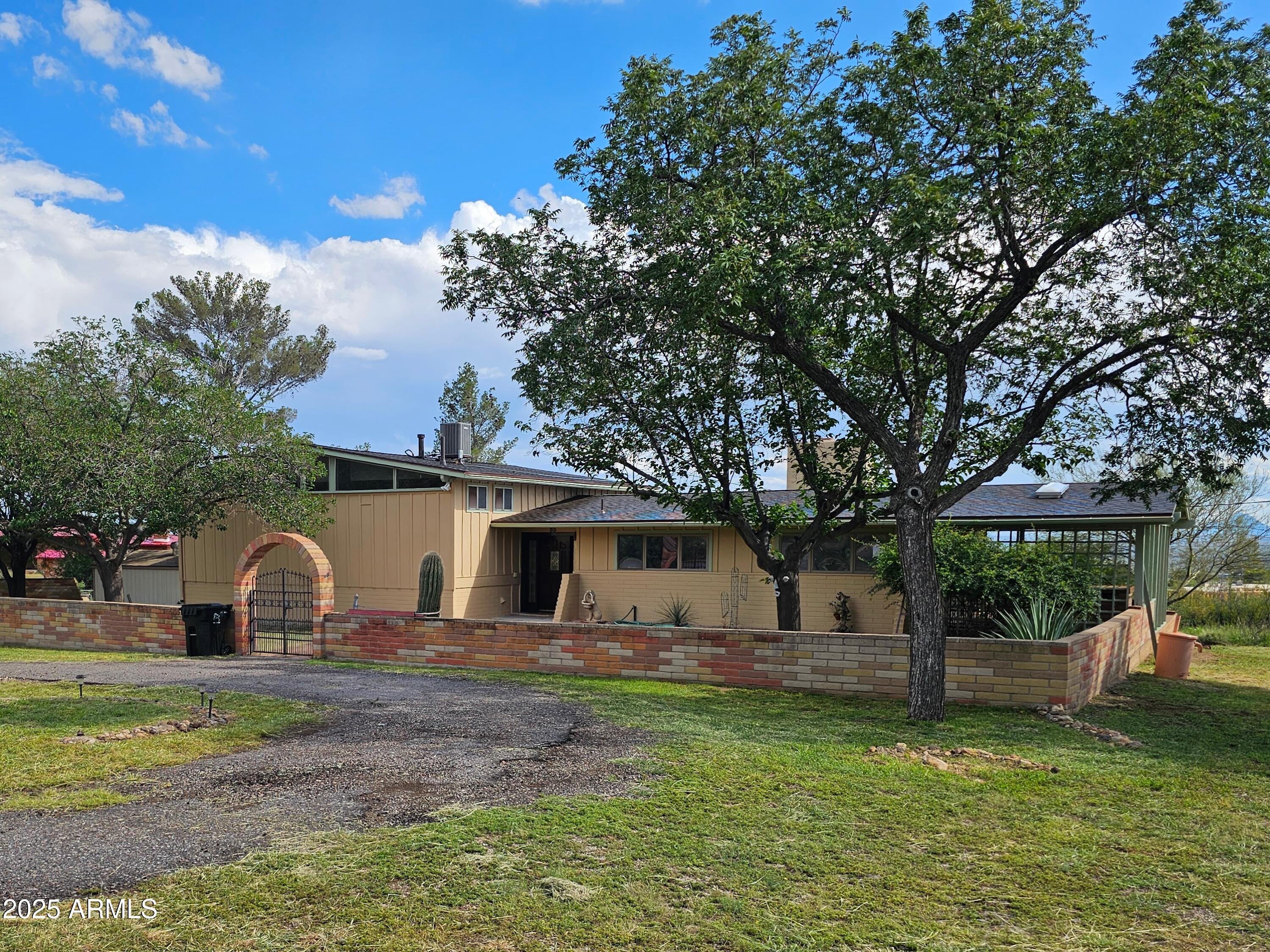 a front view of a house with garden and trees