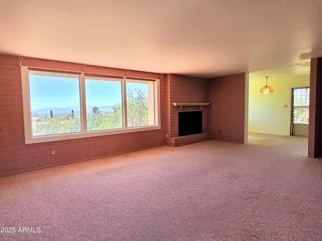 an empty room with windows and fireplace