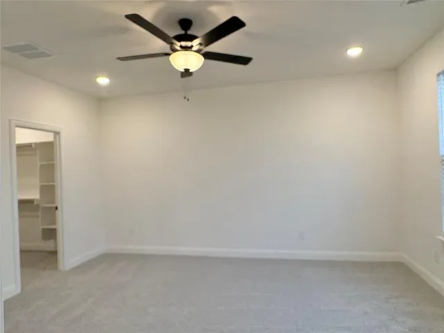 an empty room with a ceiling fan and window