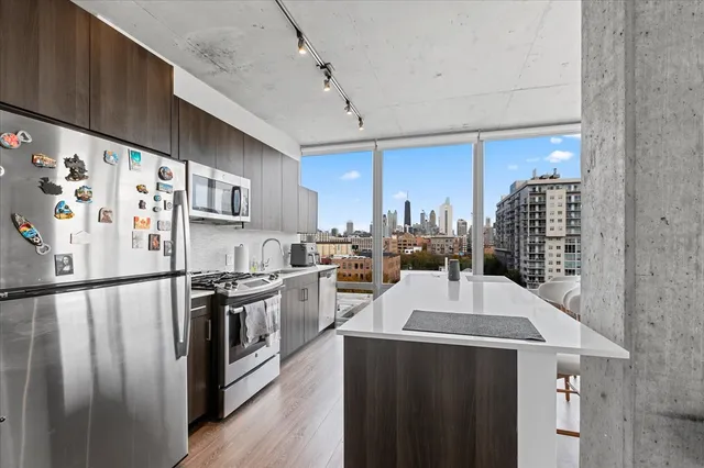 a kitchen with stainless steel appliances a refrigerator a sink a stove and white cabinets