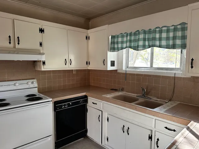 a kitchen with granite countertop a sink stove and cabinets