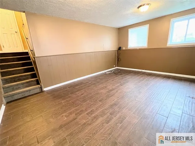 a view of an empty room with wooden floor and windows