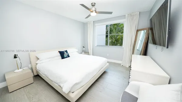 a bedroom with a bed flat screen tv and a large window