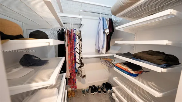 a view of walk in closet with clothes and shoes