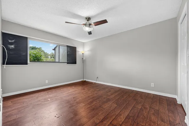 a view of empty room with wooden floor and fan