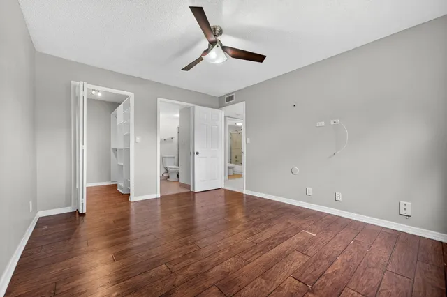 an empty room with wooden floor and a ceiling fan