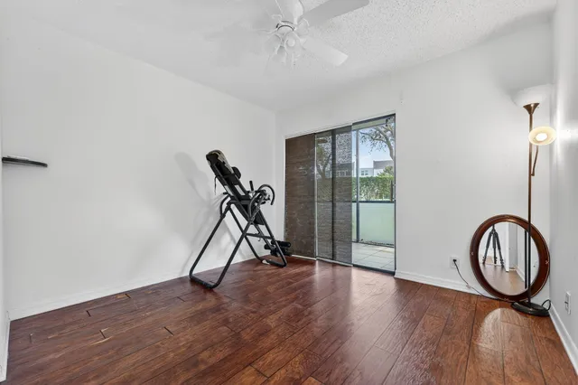 a view of a room with gym equipment and wooden floor