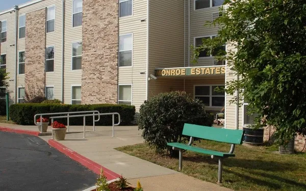 a front view of a house with a garden and bench