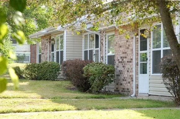 a view of a brick house with a yard and large trees