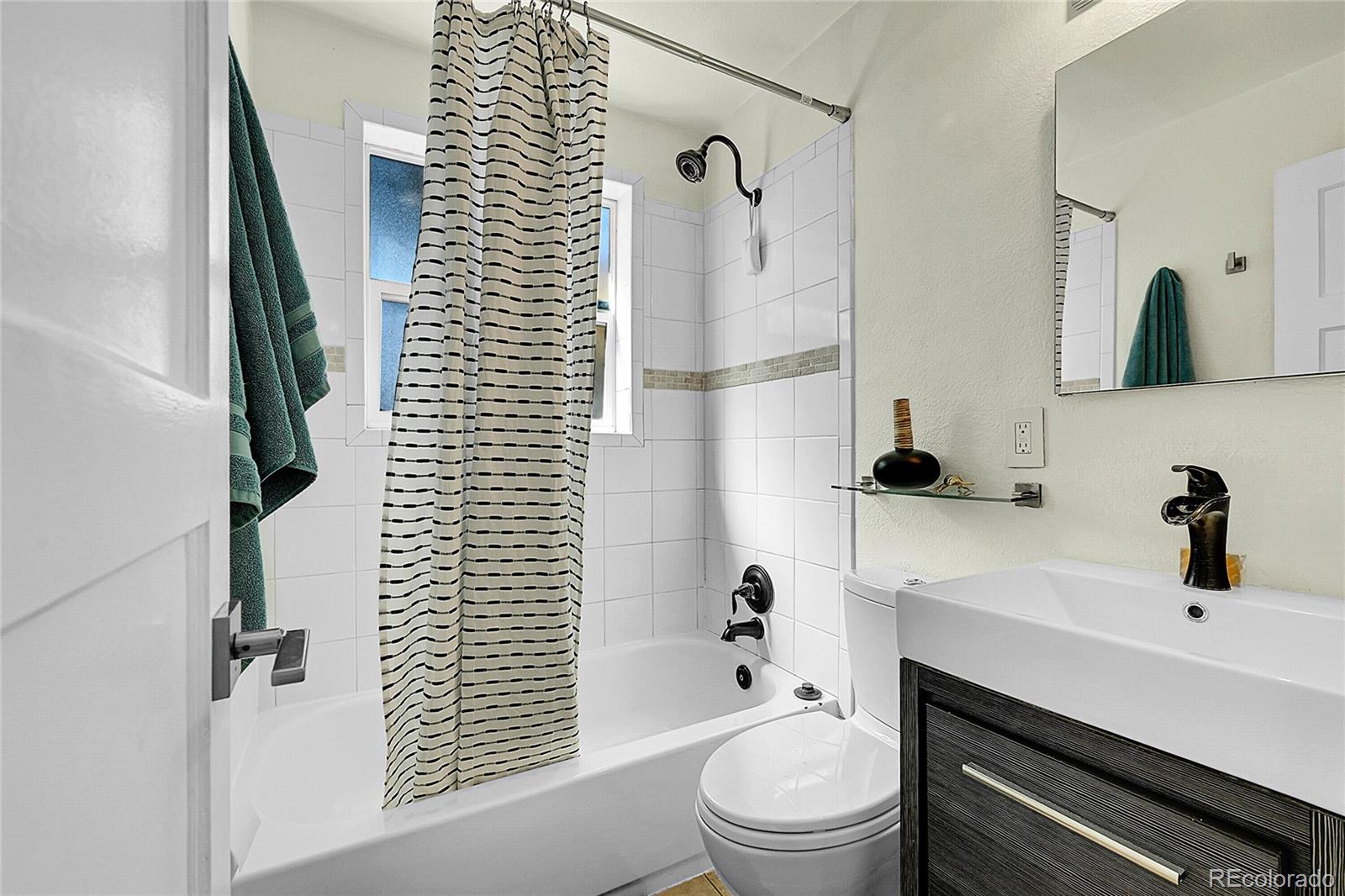 3011 Grape Street Denver, CO 80207 - Photo 22 of 42 a bathroom with a sink a toilet a shower and a mirror